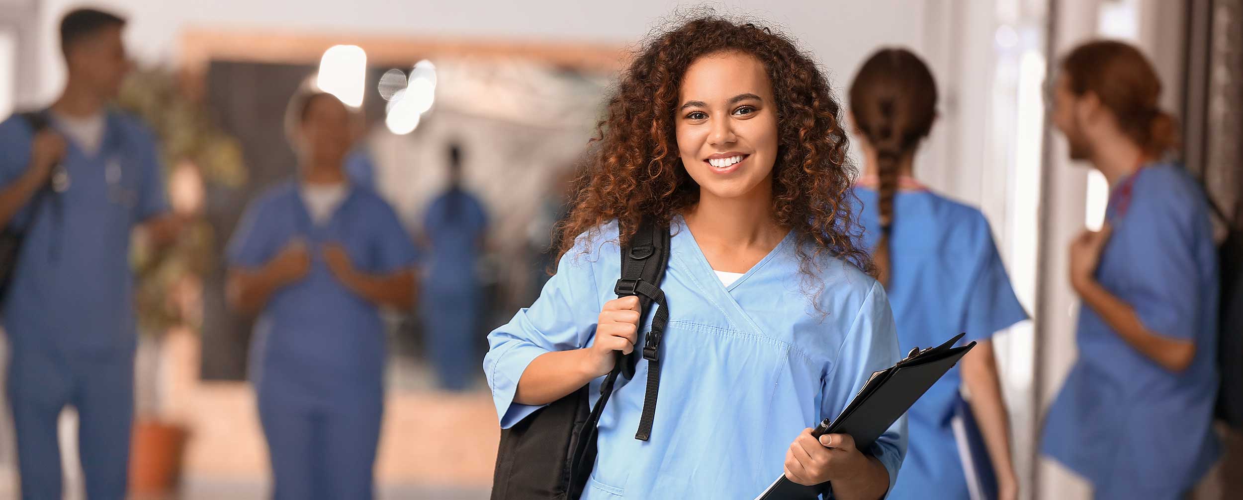 medical student holding a backpack and smiling