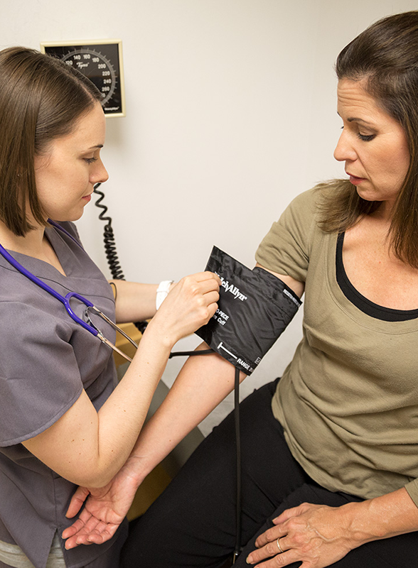 medical-assistant-or-patient-care-technician-taking-patients-blood-pressure-in-healthcare-exam-room medical-assistant-or-patient-care-technician-taking-patients-blood-pressure-in-healthcare-exam-room